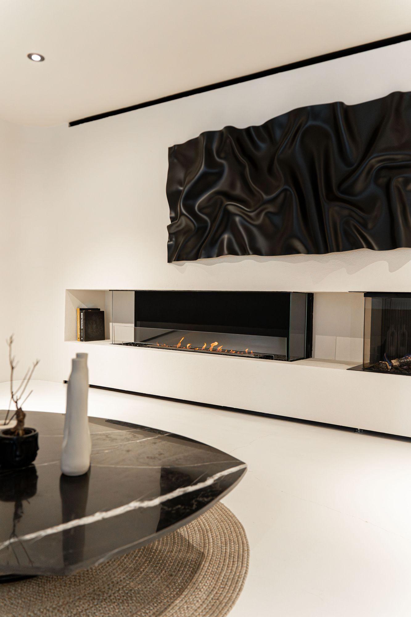 White room with a linear fireplace and a sculpted black relief