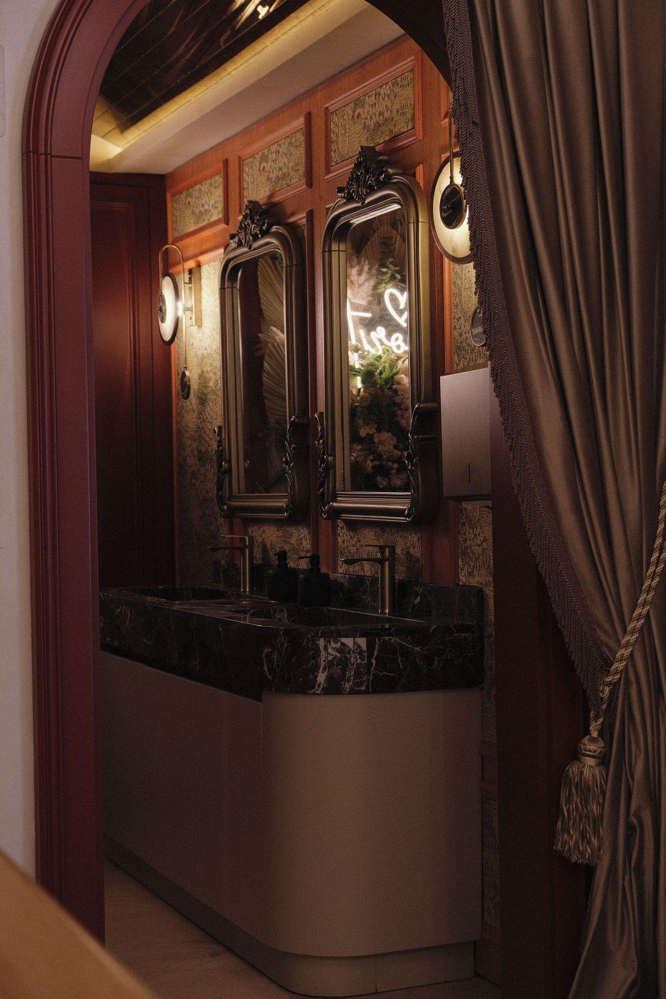 Candlelit marble vanity beneath a pair of antique bronze mirrors